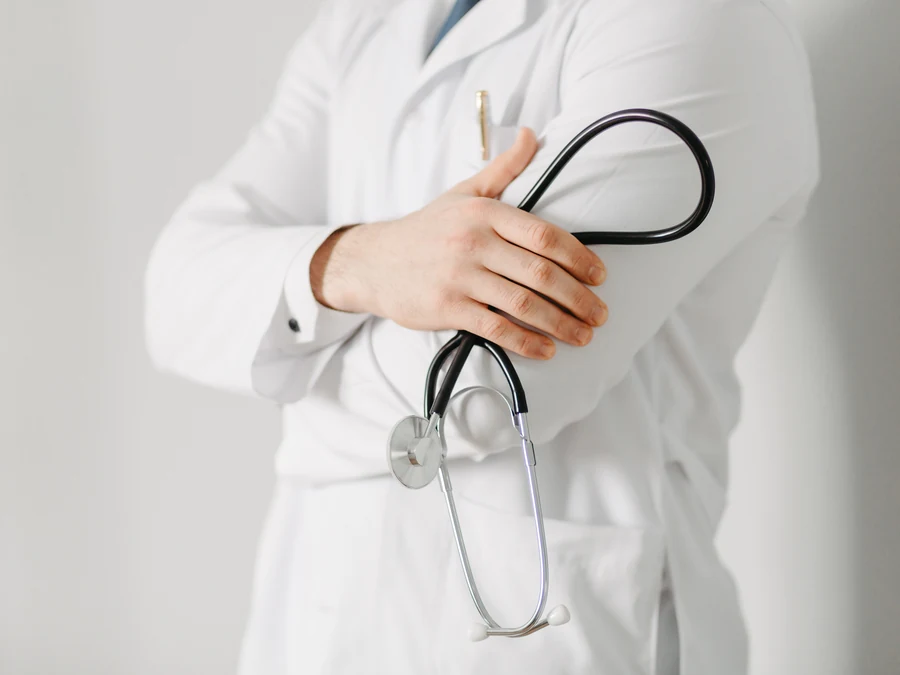 Un médecin en blouse blanche, les bras croisés, tenant un stéthoscope
