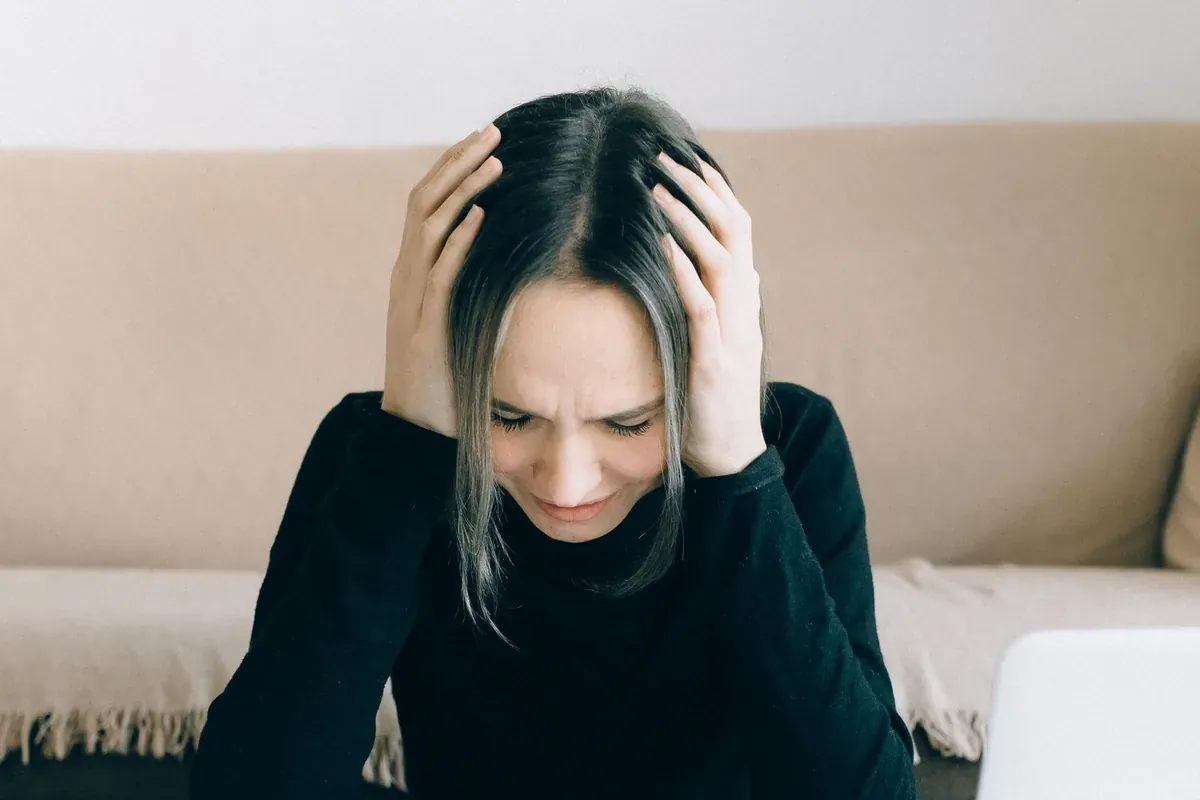 Une personne assise, la tête entre les mains