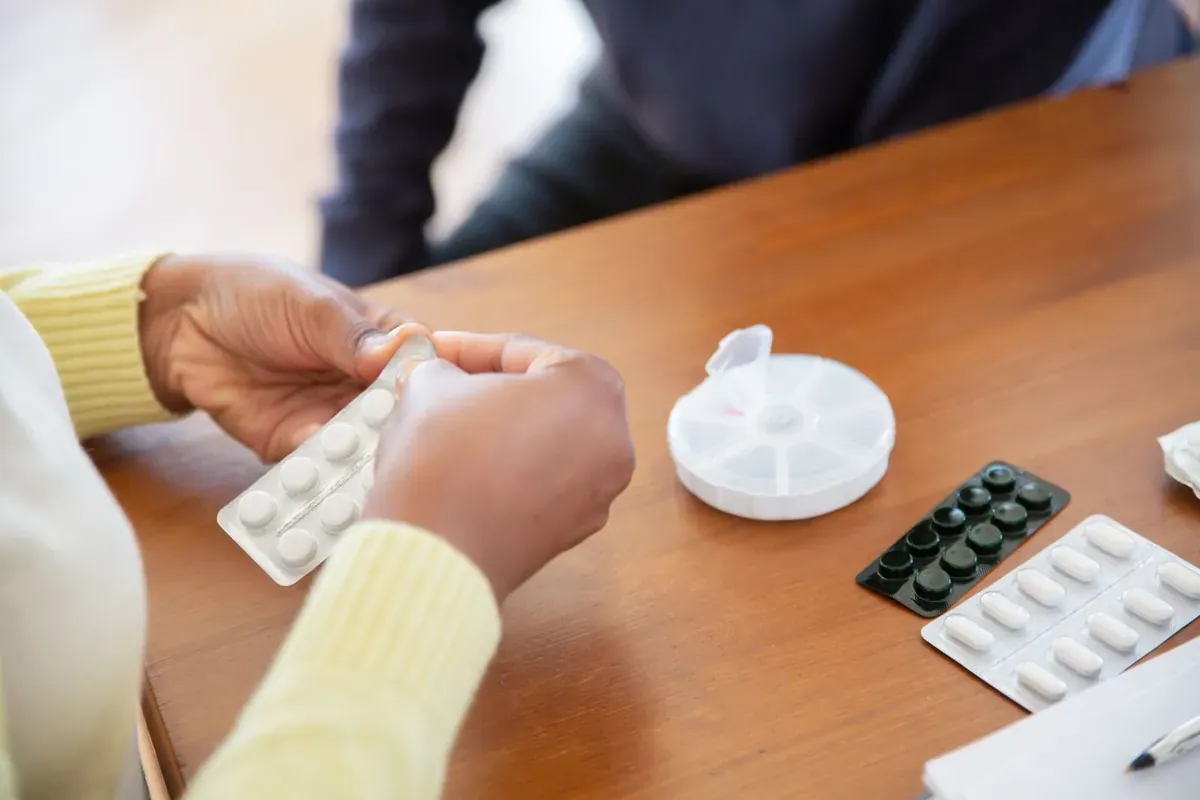 Des mains trient des comprimés depuis des plaquettes sur une table
